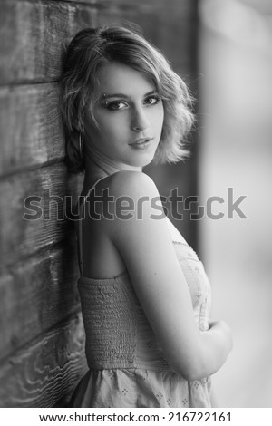 Black and white portrait of a short hair young model posing next to a wooden wall