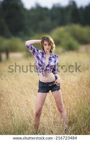 Young teen girl in tied up flannel shirt and denim shorts