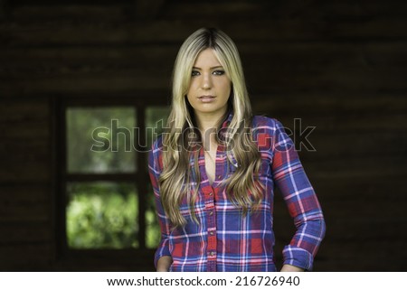 Blonde with straight hair posing inside a cabin next to a old fashion window