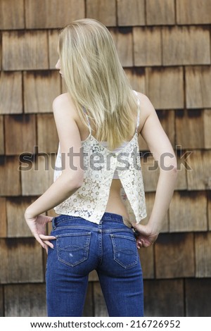 Beautiful and young blonde girl posing from behind in tight low rise jeans pants