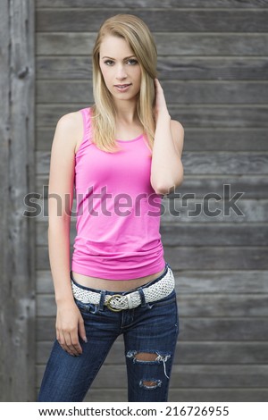 Sassy and young girl posing in casual teen outfit of white belt and ripped denim pants and pink top