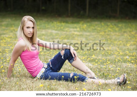 Young girl posing in casual teen outfit of white belt and ripped denim pants and pink top