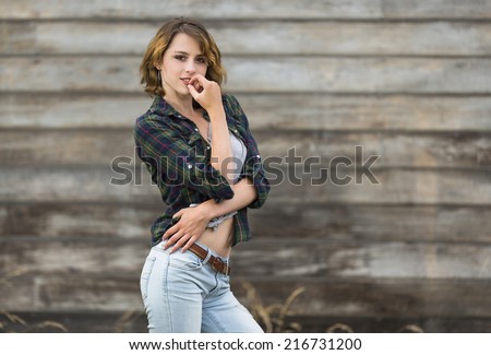 Young girl wearing flannel shirt and low rise jeans pants in a shy pose