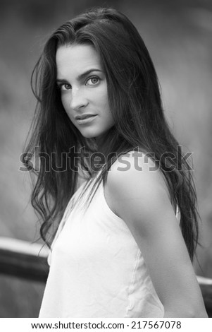 Black and white portrait of a young model with a serious look and with long brunette straight hair