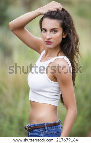 Fit young woman posing with one hand over her head and wearing a white tank top