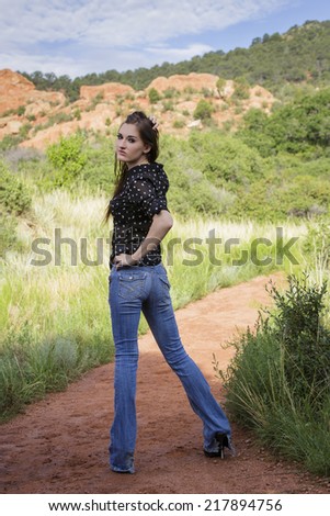 Skinny model with long legs posing from behind wearing black shirt and jeans