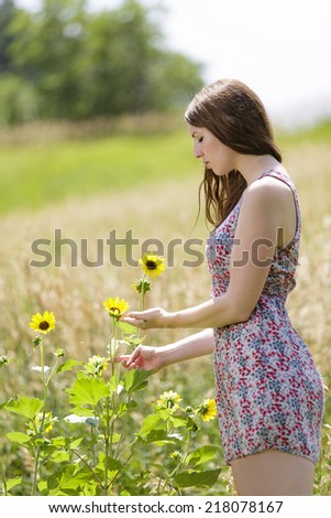 Young female model in a dress and picking some beautiful flowers outdoors