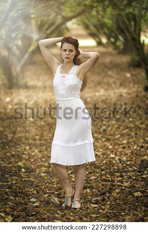 Young lady posing in a fantasy white dress in the forest