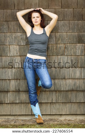 Full body portrait of a red head posing with both arms up and wearing country western wear