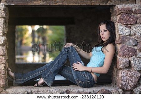 Petite young woman with long legs and high heals posing on a window or brick wall