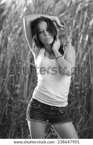 Black and white portrait of a dark hair model in white shirt and jeans shorts