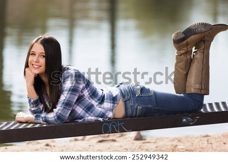 Happy young teen girl posing in a blue flannel shirt and jeans with boots
