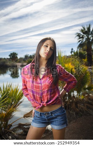 Young brunette girl in red flannel long sleeve shirt and jeans shorts with a sassy smile