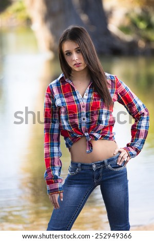 Happy young southern girl in bright red tied up flannel shirt and tight low rise jeans