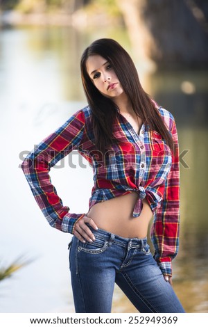 Cute young female model posing in red flannel shirt and low rise jeans pants