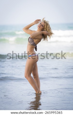 Sassy young skinny female posing in a bikini in the ocean
