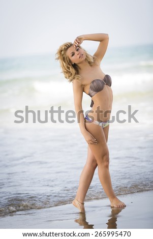 Hot young model posing at the beach in summer bikini outfit