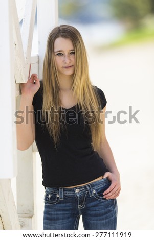 Young female model posing in dark blue jeans and black top