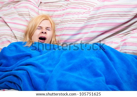 Sleepy woman yawning wrapped in a duvet.