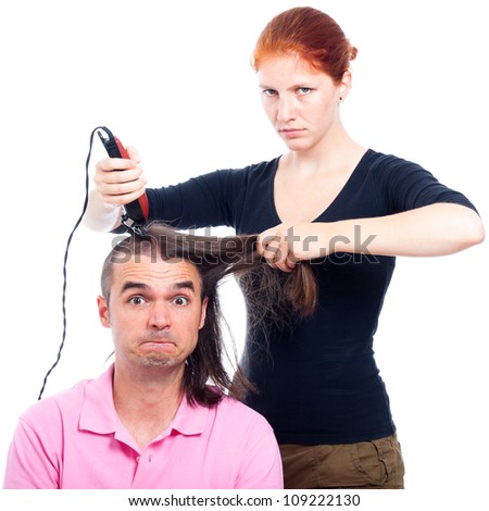Serious hairdresser woman shaving funny long haired man with hair trimmer, isolated on white background.