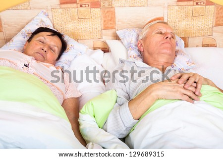 Close up of senior man and woman sleeping in bed.
