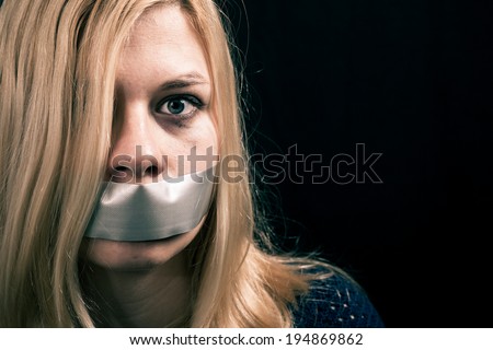 Portrait of scared kidnapped woman hostage with tape over her mouth