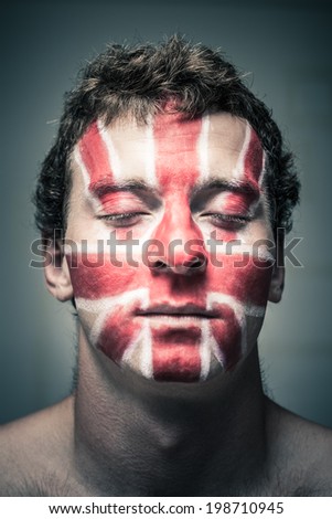 Portrait of man with British flag painted on his face and closed eyes.