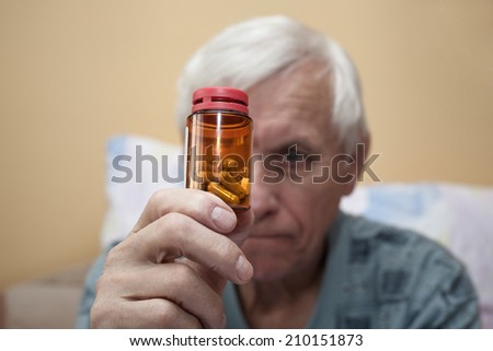 Ill senior man looking at pills.