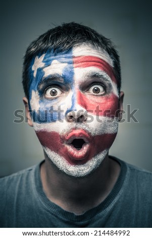 Portrait of surprised man with US flag painted on face.