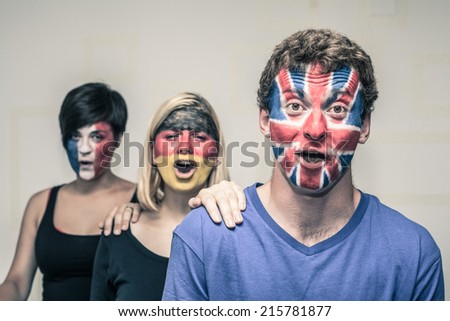 Group of excited people with painted flags on their faces shouting.