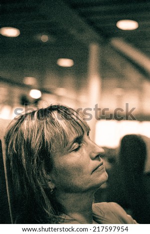 Middle aged woman sleeping in public transport. Toned grainy 35mm film scan.
