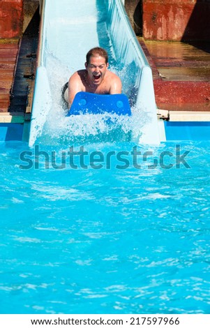 Man having fun, sliding at water park.