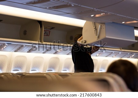 Inside an aircraft in the economy cabin. Non-recognisable person and shallow depth of field.