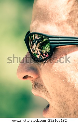 Detail of man face with open mouth wearing sport sunglasses
