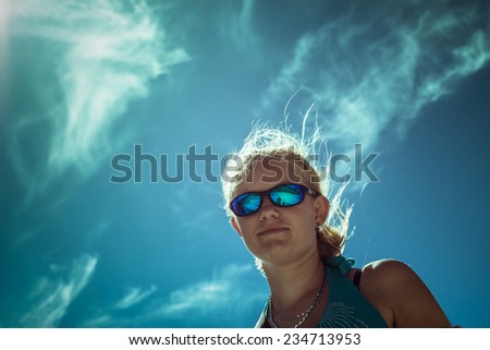 Young woman wearing sport sunglasses over bright blue sky