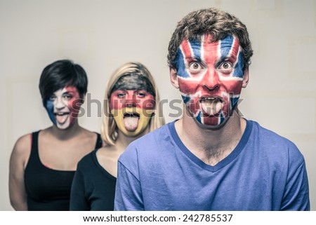 Group of funny people with painted European flags on their faces and sticking out tongue.