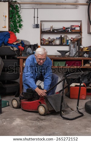 Senior worker maintaining his lawn mower in the workshop.