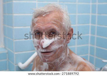 Senior man washing his body with soap in bath.