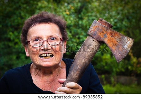 Crazy senior woman holding axe.