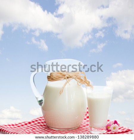 jar  full of milk  and glass in garden in sunny day with blue sky