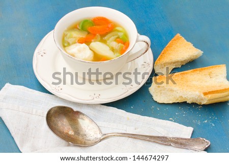 Fish soup in bowl with silver spoon on blue wooden table