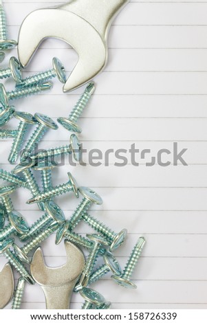 disassembled screws and wrenches on white ruled paper background with yellow tape an copy space