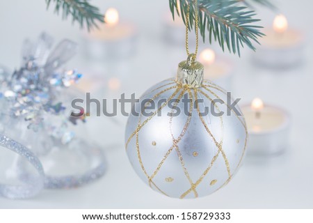silver  christmas ball hanging on fir tree and candle lights defocused background