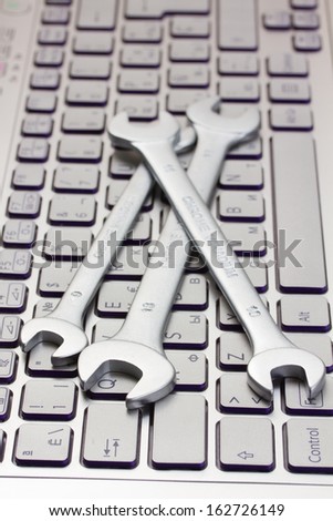 computer technical support concept - spanners on laptop keyboard