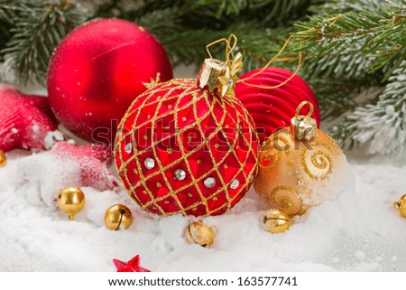 red  and gold christmas ball in snow under fir tree
