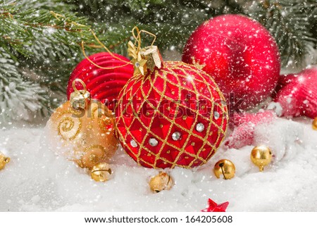 red  and gold christmas ball in snowfall under fir tree
