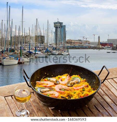 Seafood paella with glass of wine in seaside cafe port of Barcelona Seafood paella with glass of wine in seaside cafe port of Barcelona