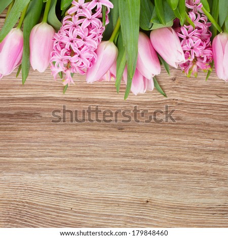 pink tulips and hyacinth flowers border on wooden table
