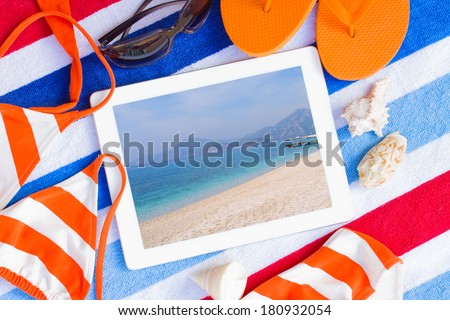 tablet on  towel with sunbathing accessories with seascape on screen