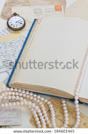 empty old book page with  antique postcards and strand of pearls vintage background with copy space